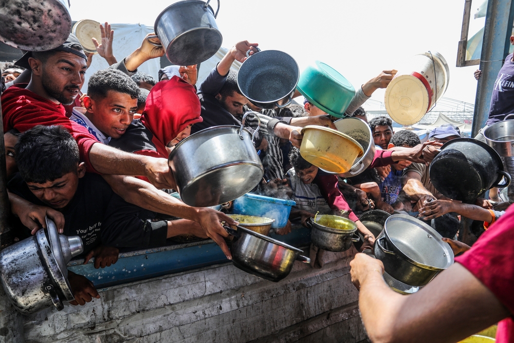 Des Palestiniens reçoivent des repas chauds d'une cuisine caritative, le 3 mai 2025