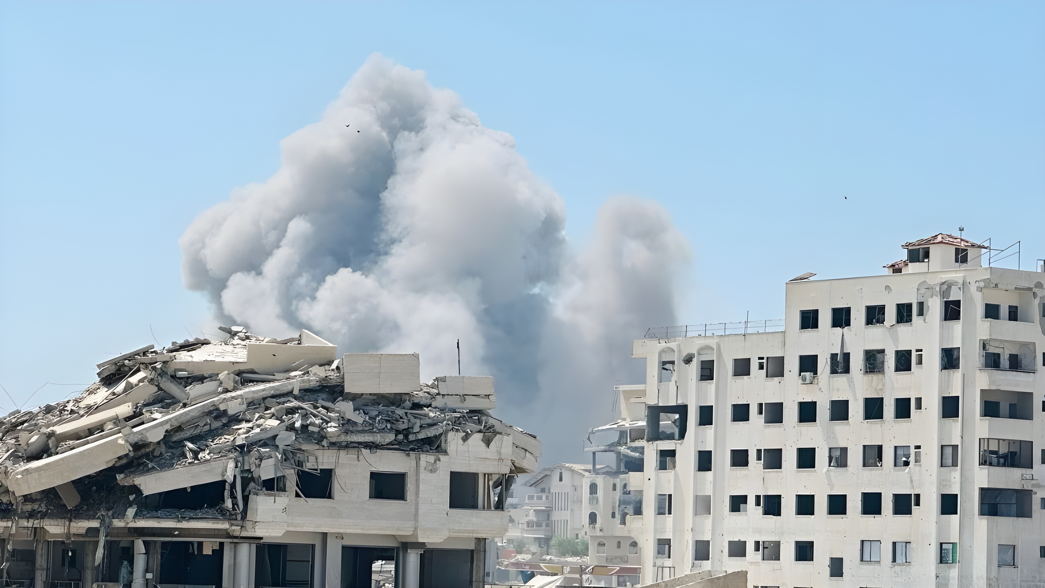 Une épaisse fumée s'infiltre derrière les bâtiments gravement endommagés de la ville de Gaza après une frappe aérienne du 19 mars 2025, montrant l'impact du conflit dans une zone résidentielle densément peuplée.