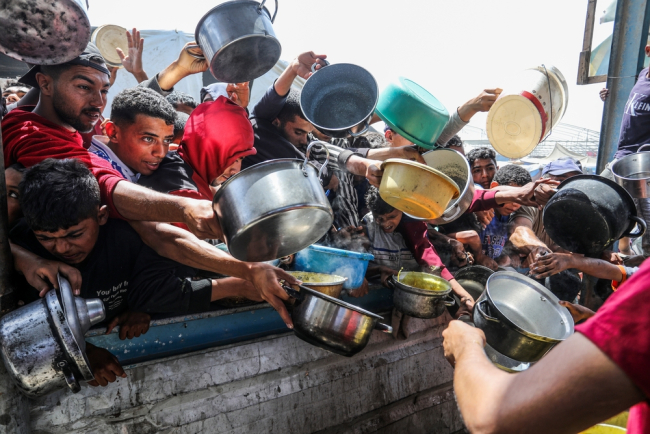 Des Palestiniens reçoivent des repas chauds d'une cuisine caritative, le 3 mai 2025