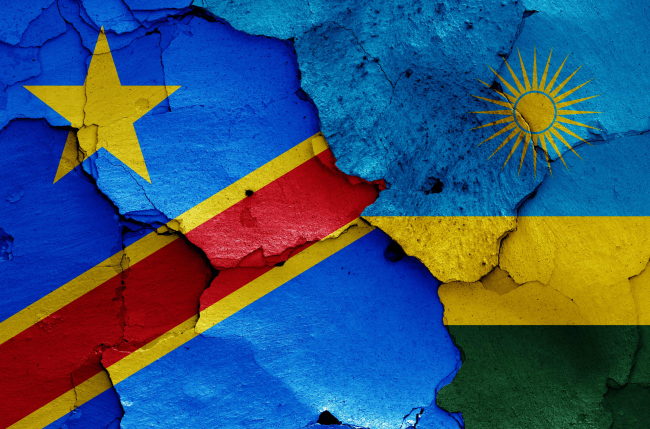 Drapeaux de la RDC et du Rwanda peints sur un mur fissuré.