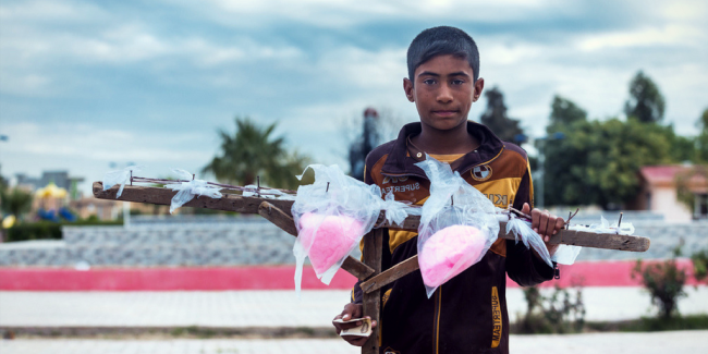 Kirkuk, Iraq - November 26, 2015: Syrian orphan in Iraq selling sweet inside park