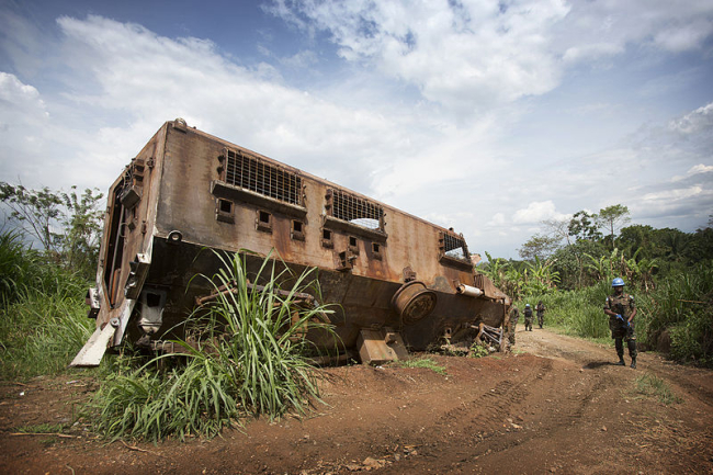 A MONUSCO Peacekeeper stands near the wreckage of a nepalese armored vehicle which was hit the previous year in an ambush from ADF militia in the Beni region, the 13th of March 2014.