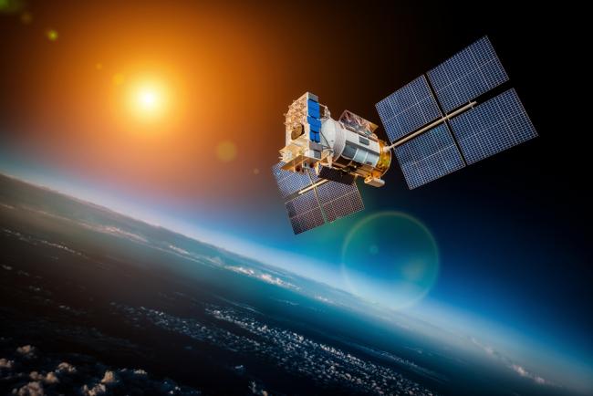 Satellite spatial en orbite autour de la terre sur fond de soleil étoilé 