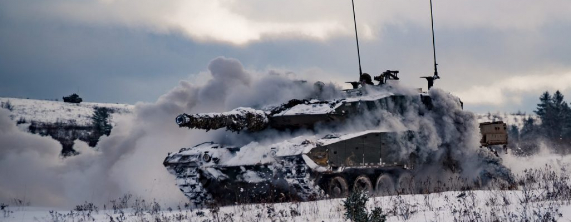 Un char Léopard des Forces armées canadiennes assaille les forces ennemies pendant l'exercice Common Ground au camp Petersville dans la zone d'entraînement de la base de soutien de la 5e division canadienne à Gagetown, 21 novembre 2018