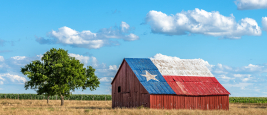 Une vieille grange abandonnée avec le drapeau du Texas peint sur le toit.