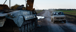 A vehicle with the sign “+”, markings often found on Ukrainian army vehicles, seen driving past a destroyed tank with the sign “Z”, markings often found on Russian military vehicles near the border of Kharkiv and Donetsk region, 2022. 