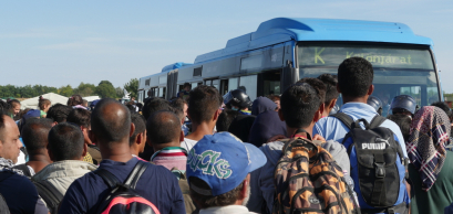Refugees wait to board a bus at a migrant collection camp in Roszke, Hungary