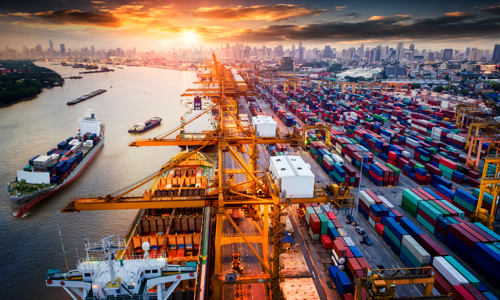 Logistics and transport of container ships and cargo planes with a crane bridge in the shipyard at sunrise, logistic export and transport industry background.